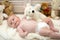 Baby lying on white duvet. Baby boy with teddy bear