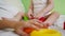 Baby and mom playing with colorful toys on the bed. Child plays in room on white bed with red and green cubes and rings.