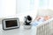 Baby monitor and camera on table near crib with child in room