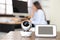 Baby monitor and camera on table and woman working in home office