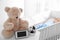 Baby monitor, camera and toy on table near crib with child in room