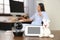 Baby monitor, camera with toy on table and woman working in home office