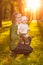 Baby with mother in the park in the rays of sunset. Toddler with mom on the nature outdoors. Backlight. Summertime family scene