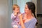 Baby on mother`s hands brushing the teeth with mother. Mother and daughter brush the teeth in bathroom. First teeth