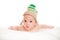 Baby newborn lying on her stomach on the bed in a funny knitted hat isolated on white background, the concept of choosing baby clo