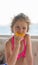 Baby with orange. Happy little girl eating orange near the sea.