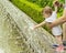 Baby pink sandals playing with water. The baby touches the water in the fountain, shoves hands under jets of water. Girl in the