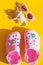 Baby Pink slippers with sunglasses on yellow background.Rubber beach shoe flat lay.Stylish beach flip-flops on color