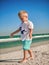 Baby playing on the seaside in summertimes. Summer rest concept. Lilltle boy having fun with the sand. Happy childhood