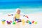 Baby playing on tropical beach digging in sand