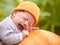 Baby with pumpkin hat sleeping on big orange pumpkin