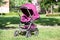 Baby pushchair is folded in lying position on green meadow in summer sunny park, an infant perambulator series