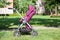 Baby pushchair is folded in seated position on green meadow in summer sunny park, side view, infant perambulator series