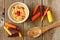 Baby rainbow carrots with hummus, overhead view on rustic wood