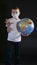 Baby reaches forward hand STOP, NO. Boy is holding a globe, a model of the planet Earth. Boy is careful of the virus