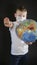 Baby reaches forward hand STOP, NO. Boy is holding a globe, a model of the planet Earth. Boy is careful of the virus