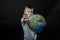 Baby reaches forward hand STOP, NO. Boy is holding a globe, a model of the planet Earth. Boy is careful of the virus. Coronavirus