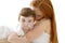 Baby and redhead mother hug on white