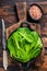 Baby romain green salad leaves in pan. Dark wooden background. Top view