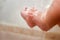Baby`s Feet Under The Shower With Lots Of Drops. Baby`s Ankle In The Water. Parents Wash Their Child`s Feet Closeup. New Born