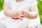 Baby`s hand holding a daisy. Cute little girl in white dress  holding white flower in hands