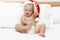 Baby with santa hat sitting on a white sofa. Christmas concept