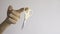 Baby scissors hanging from index finger of a woman`s left hand on a white background