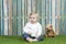 Baby seated on grass in front of a fence