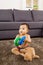 Baby seating on carpet and play doll