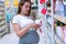 Baby shampoo pregnancy woman buy. Young pregnant woman shopping on baby bath shampoo bottle on supermarket background