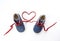 Baby shoes with laces forming heart on white background