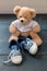 Baby shoes and teddy bear on blue wooden floor background