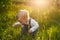 Baby sitting in the grass in sunlight. Cute summer blond girl in the garden