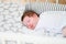 The baby sleeps in the crib. A charming baby sleeps in a crib for sleeping attached to the bed of the parents. A small child