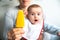 Baby smiling and drooling when trying for the first time an ice cream from his mother`s hands, infant feeding through the baby le