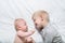 Baby and smiling older brother are lying on the bed. They play, communicate and interact. Top view