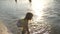 Baby splashing in the water. Splashing water. Cute child happily plays on the beach. Happy child bathes in the sunset on