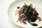 Baby squid in its black ink. Traditional Spanish tapa recipe.