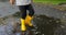 Baby stomping through puddles in yellow rubber boots