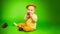Baby In a straw hat Sitting on a green background With Apple. A baby holding an apple in their hands. The baby appears