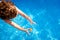 Baby swims in a pool trying to reach a toy in the water, top view in summer