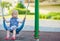 Baby swinging on swing on playground. Side view