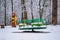 Baby swings at a playground blanketed with clean snow on a winter day in the city park