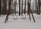 Baby swings in a snow-covered park. A deserted country park with an overcast winter day