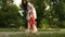 Baby takes first steps holding his mom hand and walking in park.