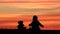 Baby and teddy bear toy silhouette sitting on grass and look at sunset sky