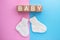BABY text on wood cubes and pair of cute knitted socks on pink-blue background. Gender of the baby. Boy or girl. Waiting foa a