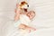 Baby less than a year lies on the bed with a soft toy. Baby in diaper lifts legs