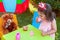 Baby toddler girl playing in outdoor tea party drinking from cup with best friend Teddy Bear