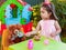 Baby toddler girl playing in outdoor tea party feeding her best friend bff Teddy Bear with a tasty lollipop